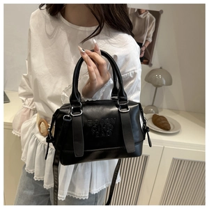 Detailed view of the black leather texture and embossed lettering on a mini Boston bag