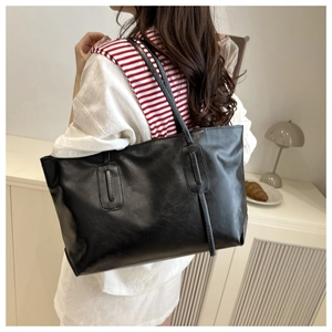 Detail view showing the soft texture and drape of a large black faux leather tote bag