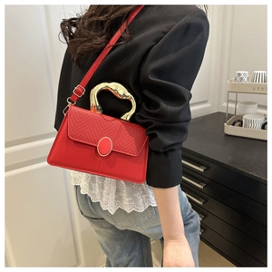 Detailed view of red leather crossbody bag with woven texture and gold metal handle