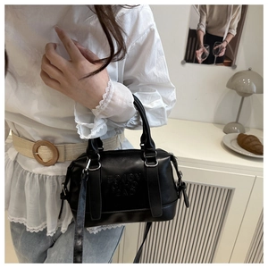 Détail du sac à main en cuir noir avec lettrage embossé et finitions métalliques argentées