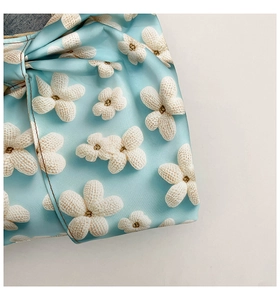 Close-up of light blue fabric bag featuring detailed white floral patterns and soft texture
