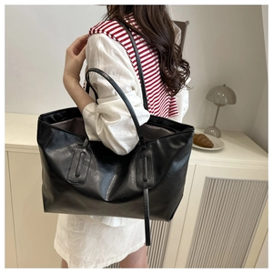Detailed side view of a large black tote bag with long shoulder straps on a model