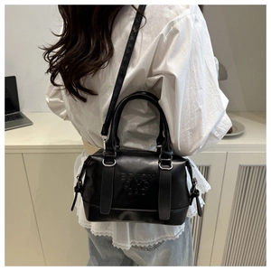 Détail du sac Boston en cuir noir avec lettres embossées et bandoulière réglable