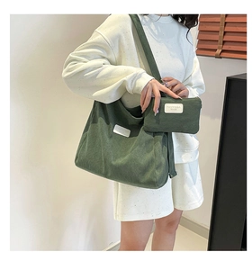 Detail of dark green corduroy tote bag and small coin purse with brand tag