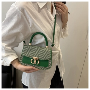Détail du sac bandoulière en tweed vert avec motif chevrons et boucle dorée sur un modèle