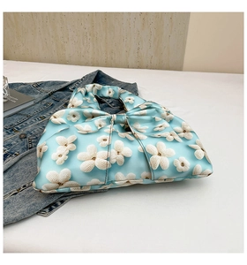 Detail of light blue satin handbag featuring white 3D floral textures and bow design