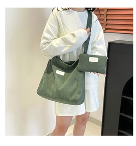 Close-up of forest green corduroy tote bag set with branded label and matching mini pouch