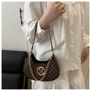 Detail of dark brown crescent bag with M-pattern monogram and large gold logo charm