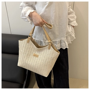 Detail of handwoven tote bag featuring brown leather straps and fashion label