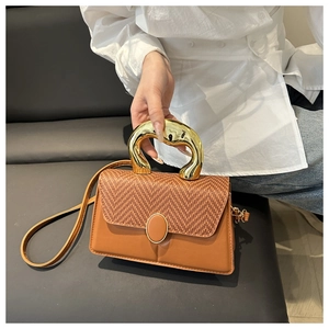 Detail of woven texture contrast on brown leather bag with golden metallic handle