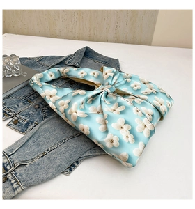 Close-up of light blue canvas tote bag with white floral pattern and oversized bow decoration