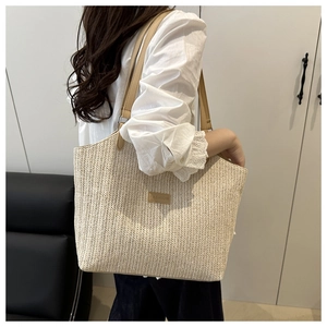 Detail of hand-woven straw tote with premium brown leather strap and brand patch