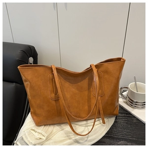 Close-up of soft brown PU leather texture and wide bottom on the tote bag detail
