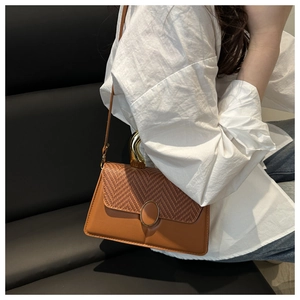 Detail of caramel leather patchwork handbag with oval metal buckle and unique gold handle