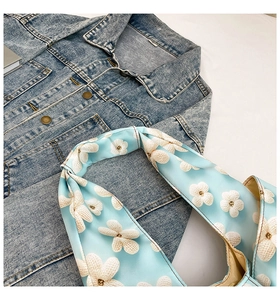 Detailed shot of a floral accessory on a denim jacket showing knit pattern details