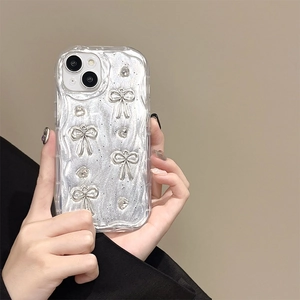 Detailed view of silver glitter phone case with 3D bows and rhinestone on wavy edge