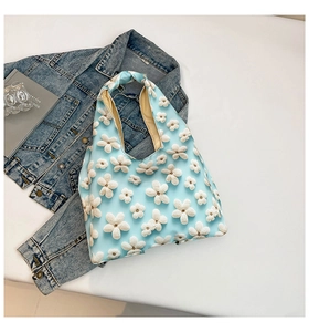 Detail of light blue tote bag featuring 3D white flower textures and integrated handles