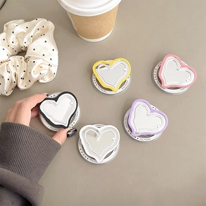 Detail of colorful heart-shaped MagSafe phone holders with mirrors on a wooden table