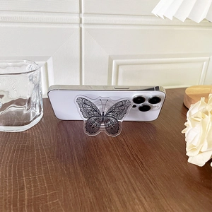 Macro detail of acrylic butterfly phone socket grip showing lace pattern and kickstand