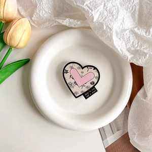 Gros plan d'un support de téléphone en forme de cœur avec motifs roses sur une assiette