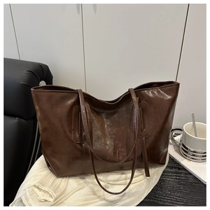 Close-up of deep brown tote bag showing smooth oil-wax leather texture and slim straps