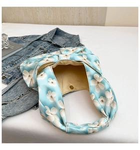 Top view of blue floral canvas bag with magnetic snap closure and beige fabric lining