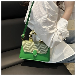 Detail of artistic gold irregular handle and green patchwork texture on a crossbody bag