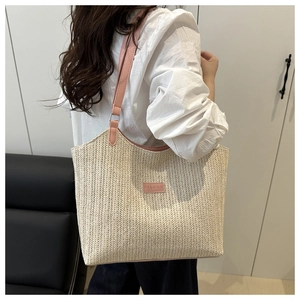Detail of hand-woven straw tote with pink leather patch and metallic ring attachment