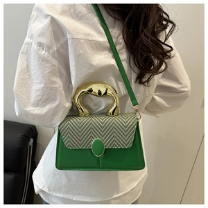 Detail of green crossbody bag showing gold metal handle and woven texture flap detail