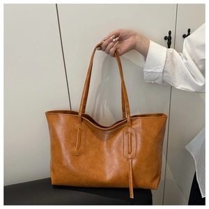 Close-up of brown PU leather bucket bag with reinforced stitching and modern tote design