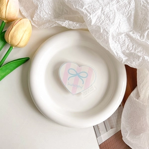 Détail macro d'un support de téléphone cœur en acrylique avec rayures roses et nœud bleu