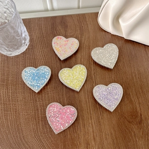 Set of six heart-shaped sequin phone grips with rhinestones on a wooden background