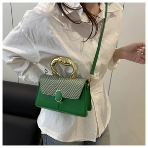 Detail of green handbag with houndstooth fabric flap and curved gold metal handle