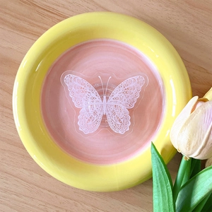 Flat lay of a decorative butterfly ceramic tray for jewelry storage on wood desk
