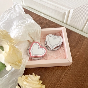 Detail of two heart-shaped magnetic phone mirror holders in a pink gift box with roses
