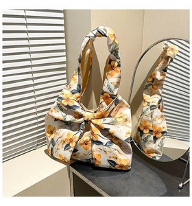 Detail of artistic fabric handbag featuring large yellow floral bow and knotted handle