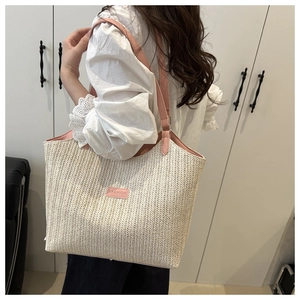 Detail of herringbone woven tote bag with pink leather trim and fashion patch