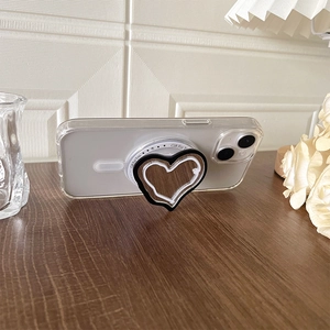Detail view of heart-shaped MagSafe phone grip acting as a stand on a wooden surface