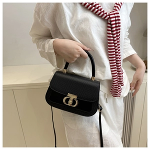 Détail du sac à main noir à motif lézard avec fermoir pivotant doré et poignées en métal