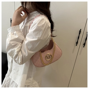 Detail of pink crescent bag with golden M logo and chain strap worn by a model