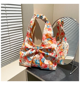 Detail of vibrant floral tote bag with a large decorative bow and wide shoulder strap