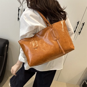 Retro large brown leather tote bag with long straps shown from a model's back view