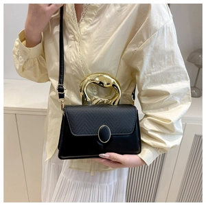 Detail of elegant black leather handbag with a unique gold sculptural metal handle
