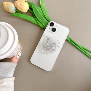 Detail of heart-shaped glitter phone grip with silver butterfly on white mobile device