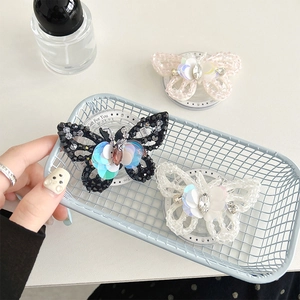 Detailed close-up of handmade beaded butterfly hair clips with shimmering sequins and rhinestones