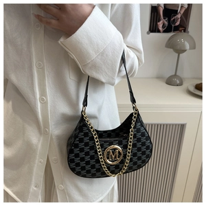 Detail of black monogram shoulder bag with gold M-logo buckle and decorative chain strap