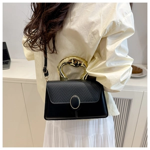 Detail of a black textured leather handbag featuring a unique gold metal handle