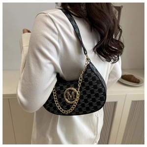 Detail of black jacquard crescent bag with golden M logo and chain strap on shoulder