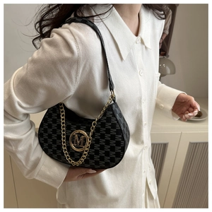 Detail of black crescent bag with M-letter pattern, gold chain and metallic logo