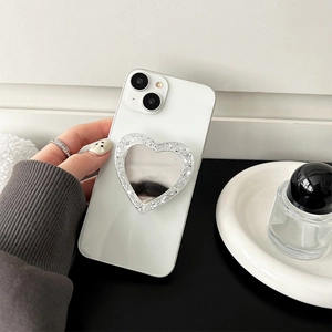 Detail of silver glitter heart-shaped phone grip with mirror on a white phone case